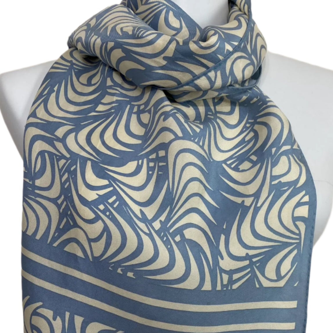 Blue and beige patterned scarf on a mannequin with a plain background