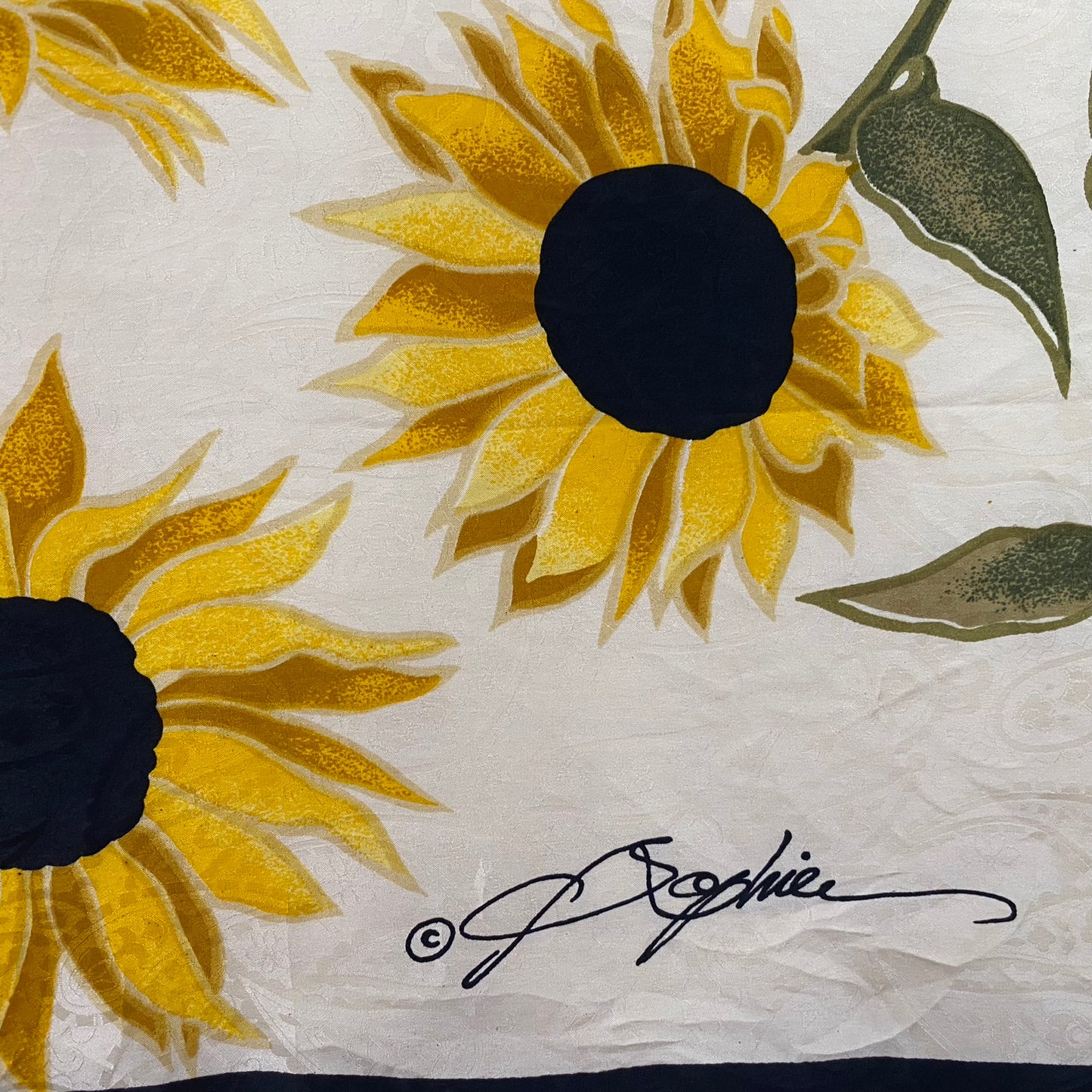 Close-up of sunflower design with a signature on a textured white background