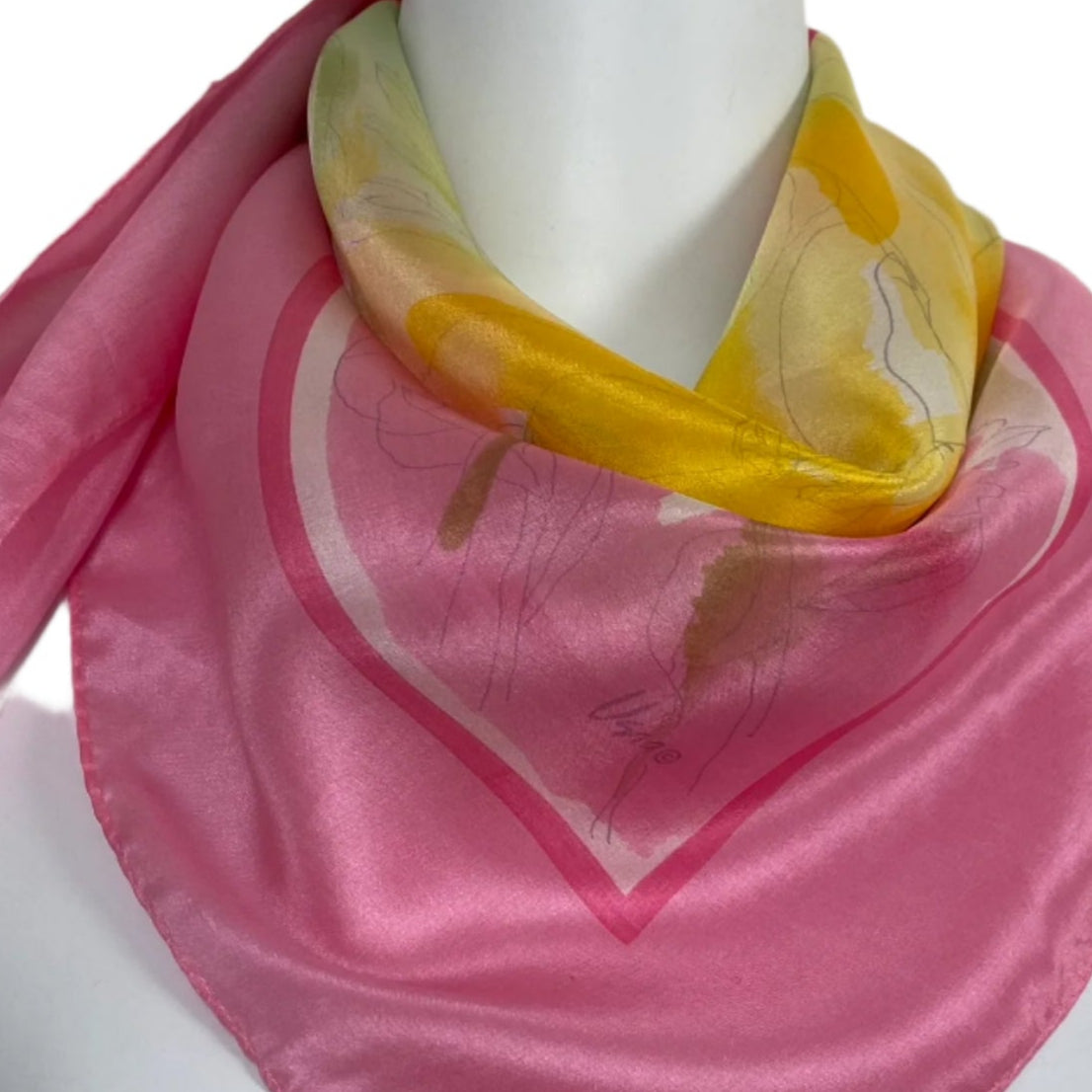 Mannequin wearing a pink Vera scarf with a colorful pattern on a plain background