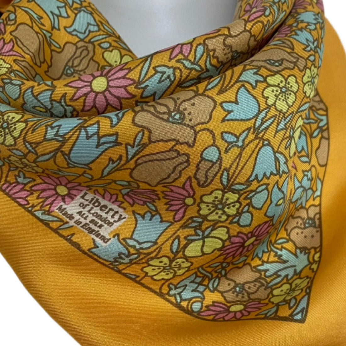 Yellow Liberty scarf with floral and animal pattern on a mannequin against a white background